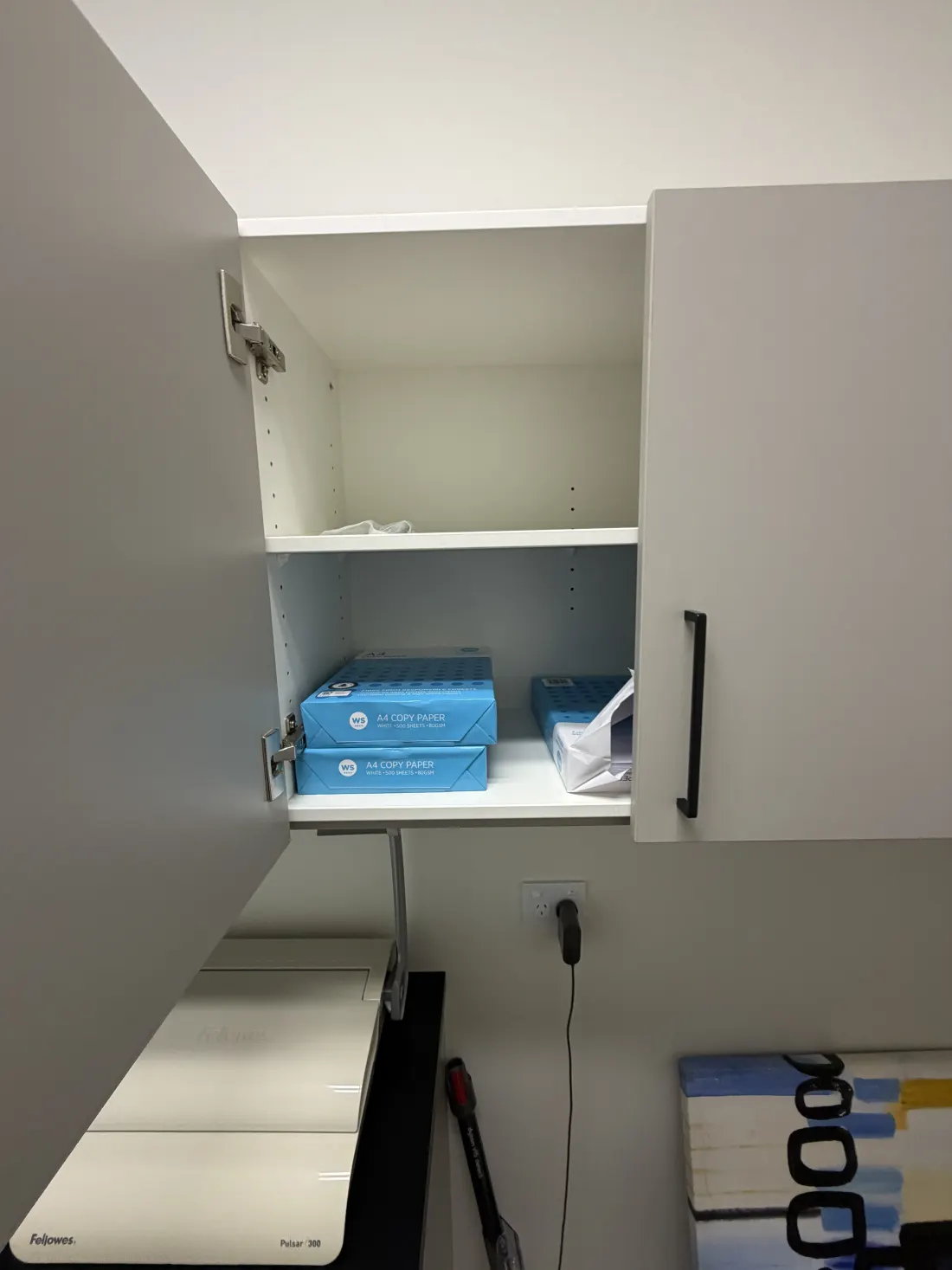 the open cupboard with the spare reams inside